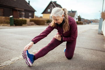 Senior woman stretching before a jog in the neighborhood