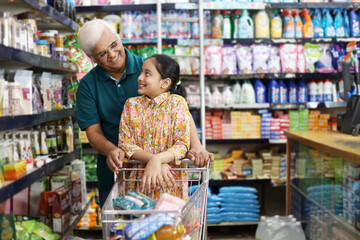 Happy Grandpa and Granddaughter enjoying purchasing in a grocery store. Buying grocery for home in a supermarket.