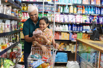 Happy Grandpa and Granddaughter enjoying purchasing in a grocery store. Buying grocery for home in a supermarket.