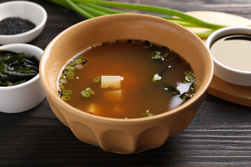 Bowl of delicious miso soup with tofu on dark wooden table, closeup