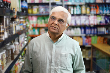 Old man standing in front of product shelf in grocery store. Confused old man buying grocery for home in supermarket. He is thinking and perplexed.