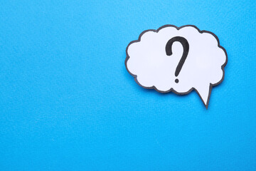 Paper speech bubble with question mark on light blue background, top view. Space for text
