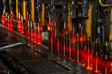 Glass factory, production of glass containers. Molten glass is blown into molds. Robotics in...