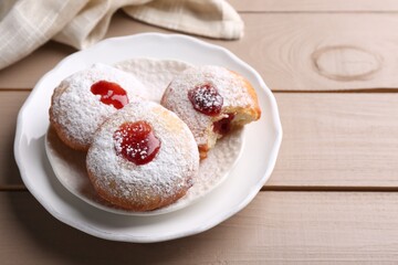 Hanukkah donuts with jelly and powdered sugar on wooden table, space for text
