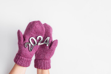 Happy New Year 2024. Hands in mittens with numbers 2024.