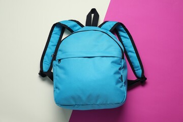 Stylish light blue backpack on color background, top view
