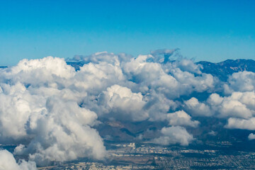 Fototapeta na wymiar Aerial photo of clouds over the San Bernardino Valley in California featuring clouds and the suburbs of Riverside County