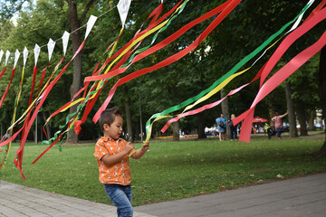 Child playing  with coloful tapes in the park outdoors