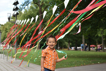 Child playing  with coloful tapes in the park outdoors