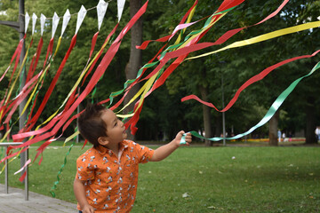 Child playing  with coloful tapes in the park outdoors