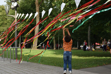 Child playing  with coloful tapes in the park outdoors