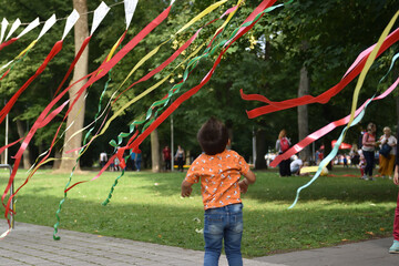 Child playing  with coloful tapes in the park outdoors