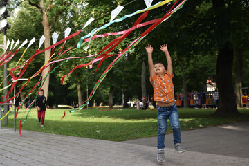 Child playing  with coloful tapes in the park outdoors