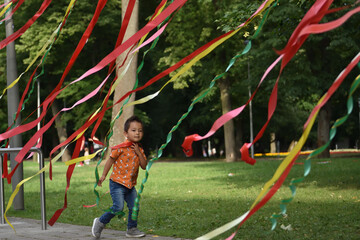 Child playing  with coloful tapes in the park outdoors