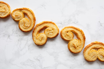 Puff pastry palmiers on a white marble table. Homemade bakery for breakfast. Picture from above.