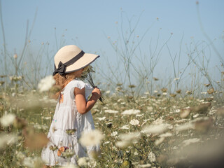 a little girl in a white sundress, without a face, a photo, a field with white flowers, a straw hat...
