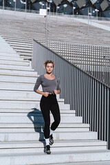 Woman athlete wearing female sportswear running and  exercising on staircase between bleachers of outdoor stadium