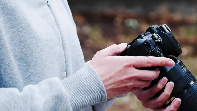 Close-up of a photographer's hands with a camera. Photographer checking a digital SLR camera on the street.