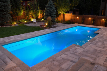 Lights in swimming pool and backyard patio and deck at night - obrazy, fototapety, plakaty