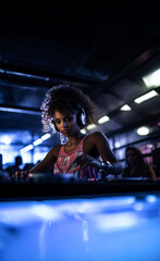 Fototapeta na wymiar Young African American DJ woman playing music in a nightclub with neon lights