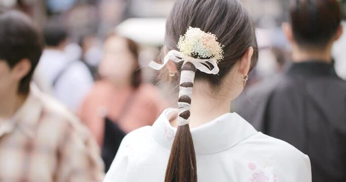 Girl with kimono and traditional hairstyle walking through the crowd