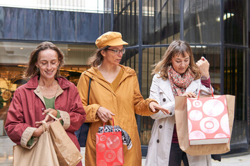 Group of mature women talking while walking on a mall after shopping day