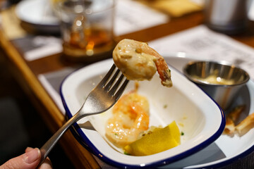A dish of freshly prepared grilled shrimp with sauce and lemon in a white plate.