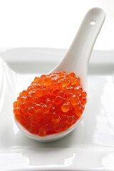 Salmon red caviar in white ceramic spoon