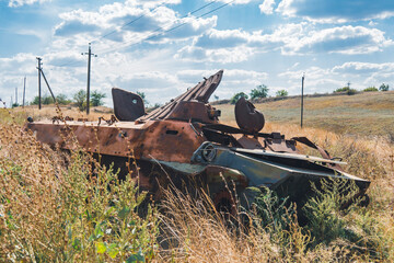 Countryside. Destroyed burnt combat vehicle stands on the side of the road. War in Ukraine - obrazy, fototapety, plakaty