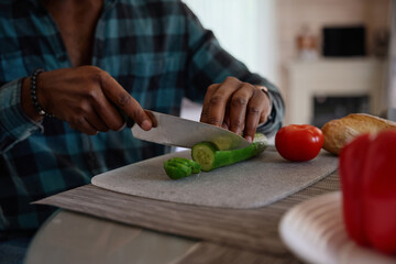 African American guy is preparing a salad from juicy vegetables