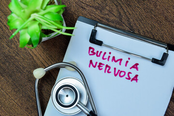 Concept of Bulimia Nervosa write on paperwork with stethoscope isolated on Wooden Table.