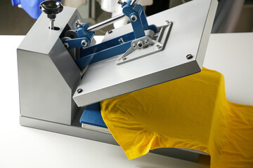 Printing logo. Heat press with yellow t-shirt on white table