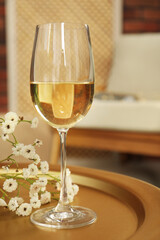 Glass of white wine and flowers on table in room. Relax at home