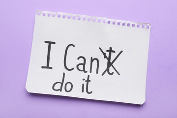 Motivation concept. Changing phrase from I Can't Do It into I Can Do It by crossing out letter T on violet background, top view