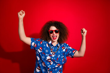 Photo of lucky excited woman wear ugly santa claus print x-mas shirt screaming yes isolated red color background - obrazy, fototapety, plakaty