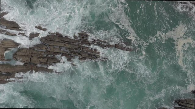vista superior desde dron, mostrando la rompiente de las olas sobre las rocas