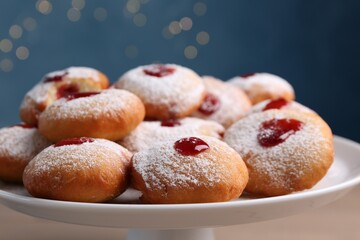 Hanukkah donuts with jelly and powdered sugar on stand against blurred festive lights, closeup