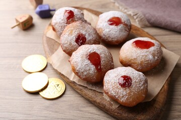 Hanukkah donuts, dreidels and coins on wooden table