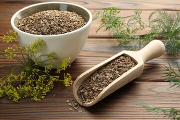 Scoop of dry seeds, bowl and fresh dill on wooden table