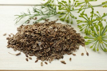 Dry seeds and fresh dill on white wooden table, closeup