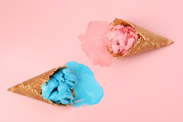 Melted ice cream in wafer cones on pink background, flat lay