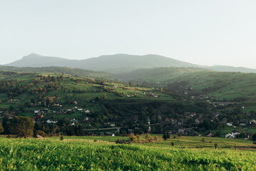 Meadow with green grass and mountains with village view Yasinya, Zakarpattia