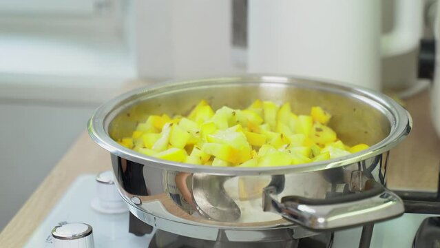A woman adds feta cheese to a dish she prepares with zucchini. Close-up.