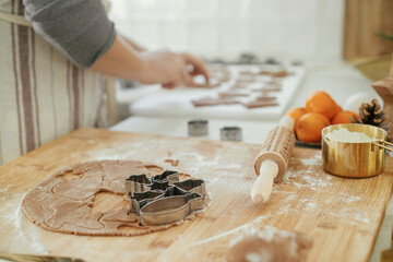 Man making christmas gingerbread cookies close up in modern white kitchen. Hands cutting...