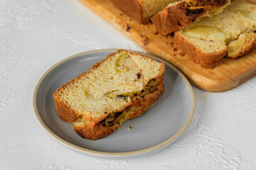 Close-up of a slice of freshly baked apple fruit cake on a plate, sliced cake on a cutting board