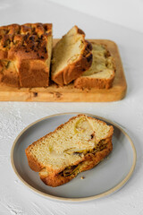 A slice of freshly baked apple fruit cake on a plate and sliced cake on a wooden cutting board