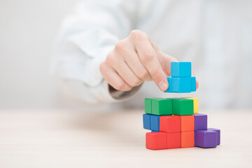 Man's hand stacking colorful wooden blocks. Business development concept