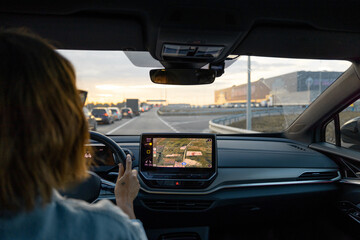 Woman drives modern electric car on a highway with lots of cars at sunset. Concept of modern vehicles and traveling by car