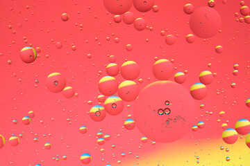 Macro photo with circles oil droplets water surface. Abstract yellow and red background with oil bubbles.