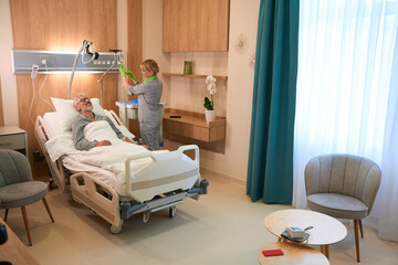 Clinic employee prepares an IV for an elderly man